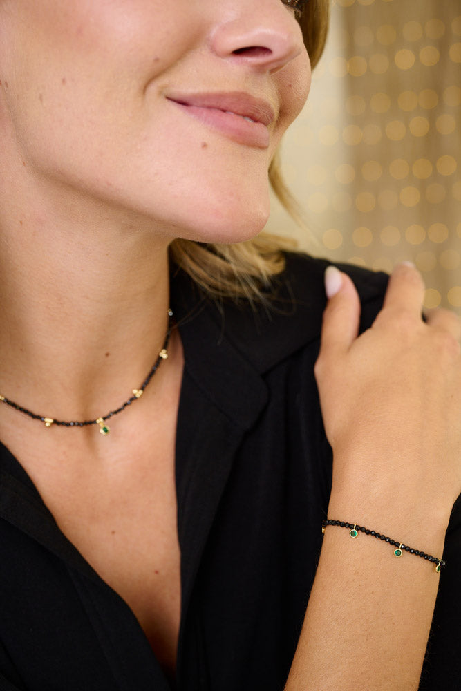 Holly Gold & Black Spinel Gemstone Charm Bracelet styled on the wrist, featuring black Spinel beads, green charms, and gold accents, Pictured alongside the matching jasmine black spinel necklace. Perfect for layering or wearing solo.