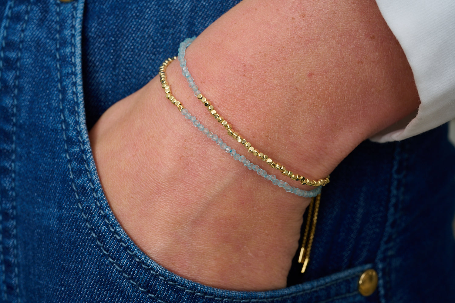 Juniper Gold & Blue Topaz Double Strand Bracelet featured on wrist with Boho Betty stacking bracelets in gold and blue gemstone tones.
