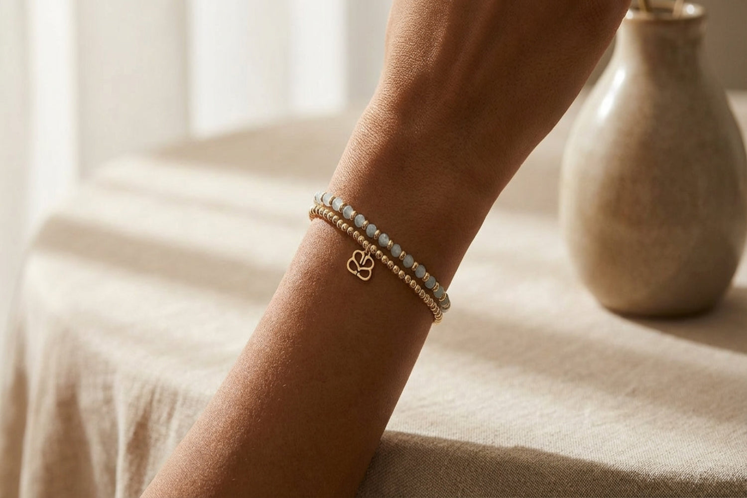 Close-up of Bluebell Gold & Aquamarine bracelet on diverse skin tones, showing faceted beads and gold accents, in a relaxed pose.