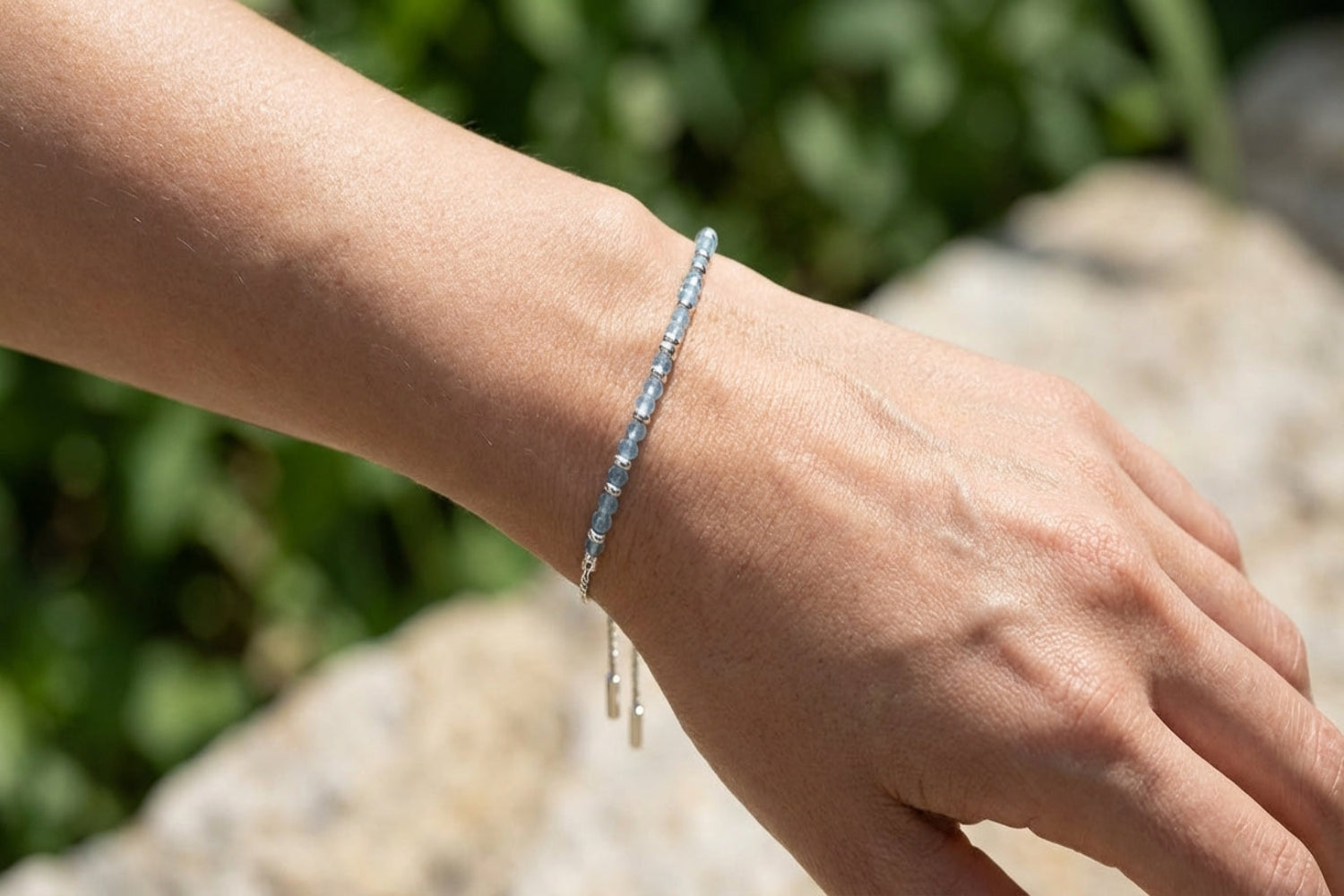 Silver bracelet with blue topaz gemstones on a model's wrist, showcasing its delicate design and sparkle