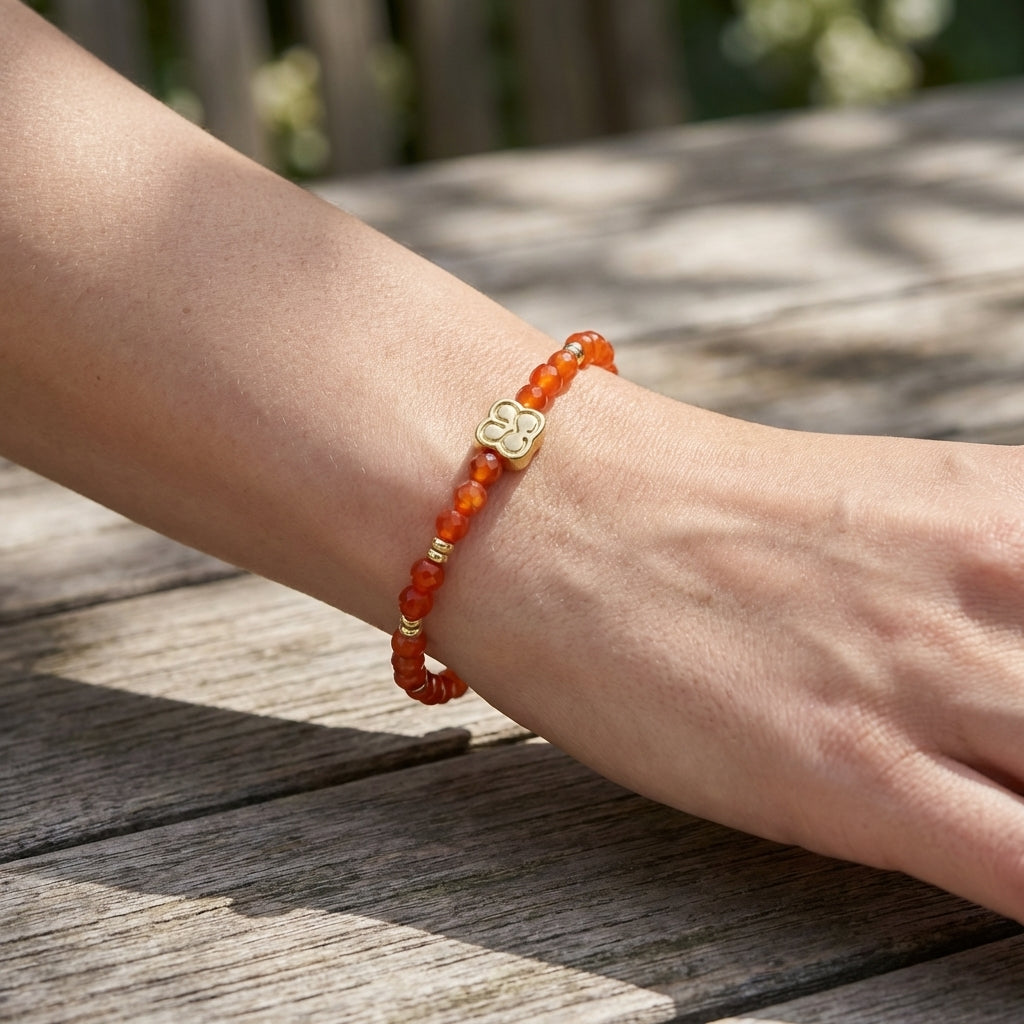 Close-up of a delicate orange agate gemstone beaded bracelet with gold accents on a rustic wooden table outdoors, highlighting micro-facets and shimmer.
